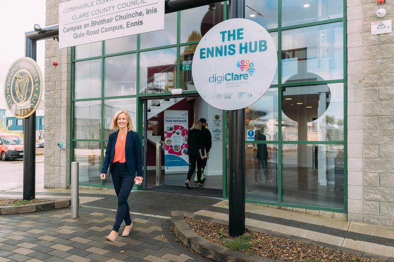 This images shows a woman standing beside a sign that says "The Ennis Hub".